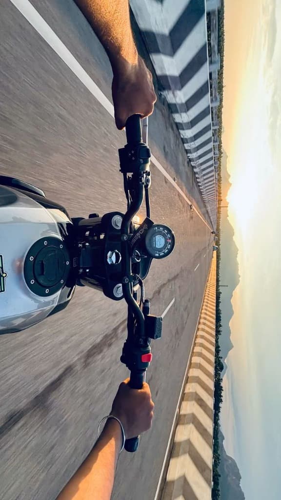 Motorcycle rider perspective on scenic highway at golden sunset